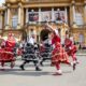 Folklorni plesači u raskošnim crvenim i crnim kostimima nastupaju ispred Hrvatskog narodnog kazališta u Zagrebu.
