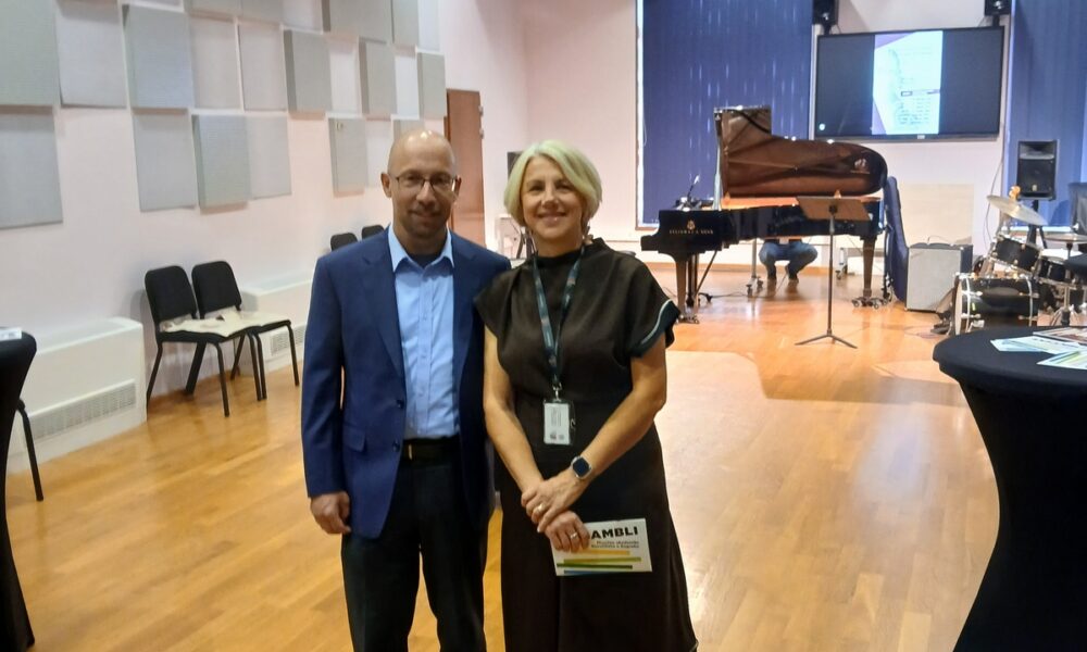 Muškarac i žena poziraju u dvorani s klavirom i glazbenom opremom u pozadini.