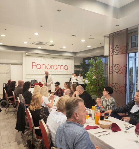 Fotografija prikazuje članove i goste Udruge slijepih USKA tijekom godišnje skupštine i zajedničkog druženja u Restoranu Panorama u Karlovcu. Sudionici sjede za svečano postavljenim stolovima i prate program, a u pozadini se vidi predsjednik udruge. Ugodna atmosfera i okupljanje za istim stolom ističu važnost zajedništva, druženja i međusobne podrške.